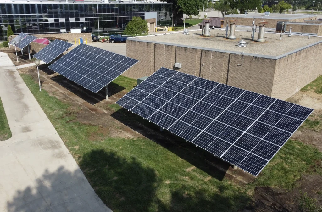 A series of 5 solar panels ground mounted near a commercial building
