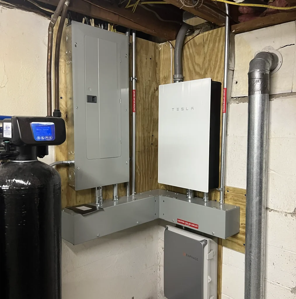Tesla powerwall mounted on plywood in a basement